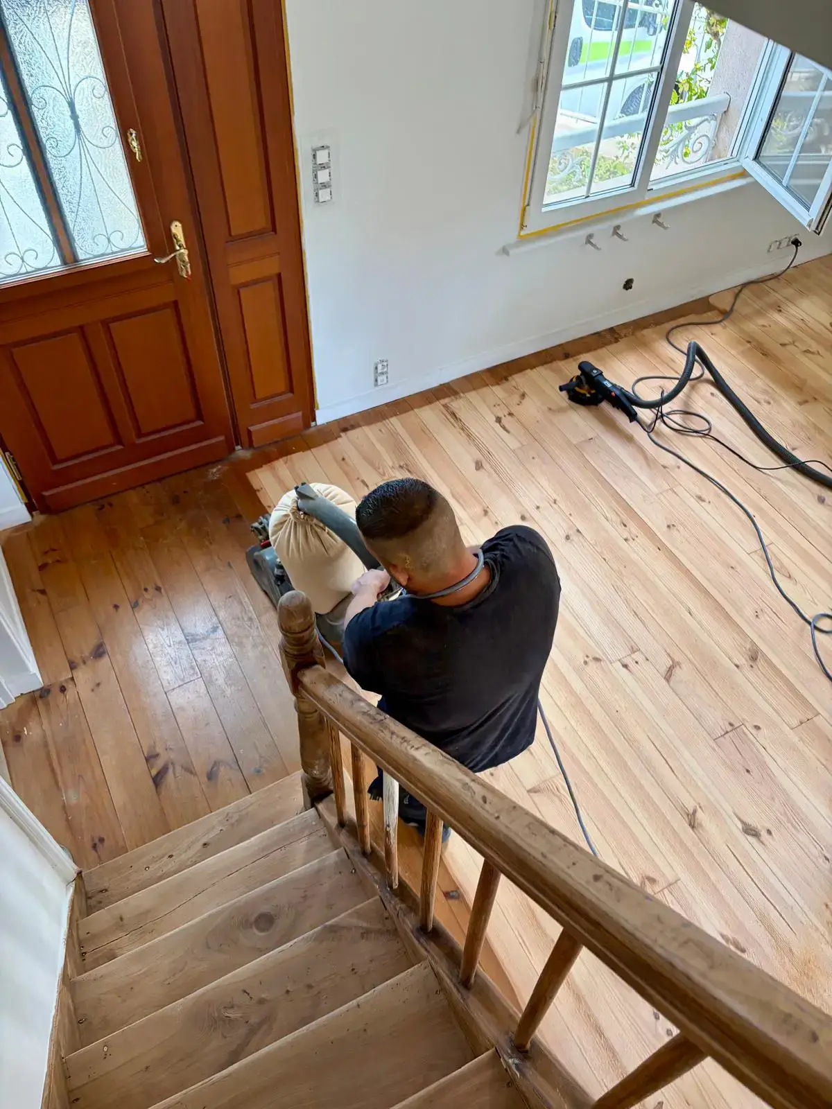 Chantier de rénovation de parquet dans une pièce lumineuse en cours de travaux